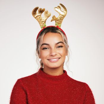 Christmas gives us an opportunity to pause and reflect. Studio shot of a young woman wearing a reindeer headwear against a grey background.