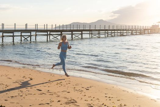 woman running on beach in morning sunrise fitness workout sport.