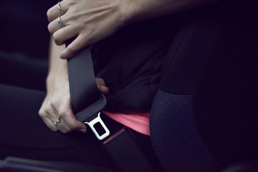Wherever you go, go safely. Shot of an unidentifiable young woman buckling her seatbelt while sitting in her car.