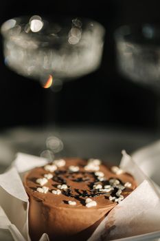 Close-up of chocolate bento cake with white candle and chmpagne glasses on luxury marble table