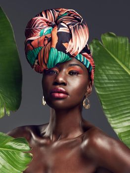 More than just cloth, its my crown. Studio shot of a beautiful young woman wearing a traditional African head wrap against a leafy background.