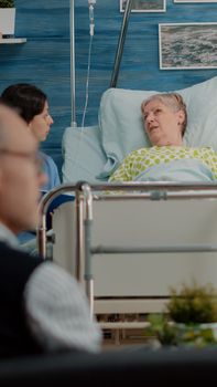 Senior patient with sickness talking to nurse about treatment