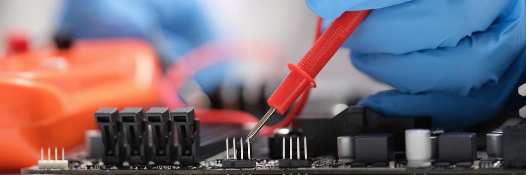 Master repairer testing motherboard with feeler gauge closeup