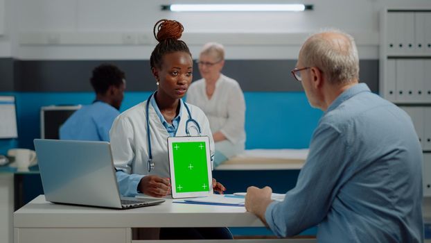 Medic showing green screen on tablet to senior man