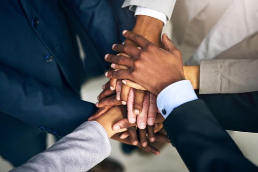 Bring it in, team. High angle shot of a group of unrecognizable businesspeople joining their hands together in unity.
