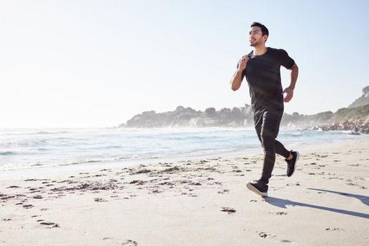 One step in front of the other. Full length shot of a handsome young male athlete out for a run on the beach.