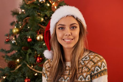 Happy Christmas everyone. Shot of an attractive young woman wearing a Christmas hat on Christmas day.