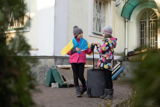 Ukraine military migration. two little girls with a suitcase. Flag of Ukraine, help. Crisis, military conflict