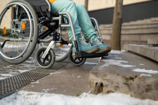Woman in a wheelchair near the stairs in the park in winter.