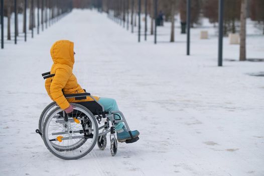 Disabled woman in a wheelchair outdoors in winter.