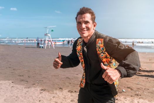 Latin mature dancer in rumba outfit on the beach giving thumbs up and smiling
