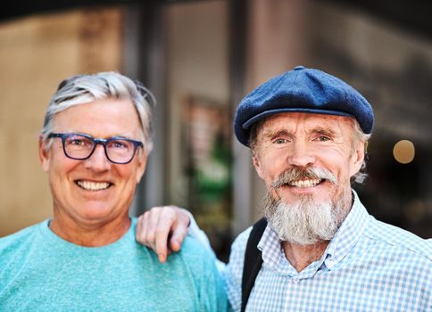 True friendship only gets better with age. Portrait of two senior friends posing together outside their favorite cafe.