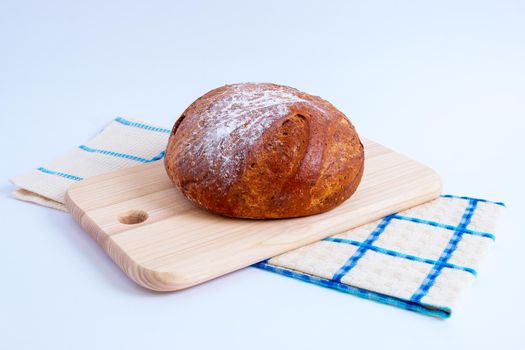 round bread on a cutting board and a tea towel