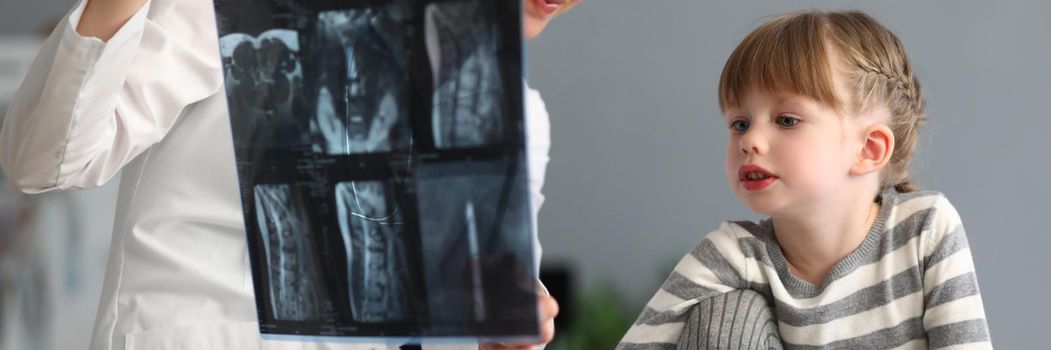 Woman doctor shows little girl an X-ray of spine