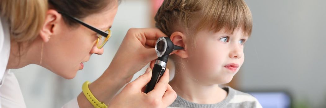 ENT doctor conducts physical examination of little girl ear