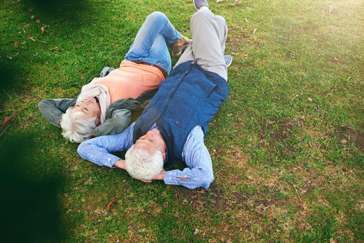 Retirement is a time for reflection. Shot of a senior couple lying down on the grass and looking up at the sky.