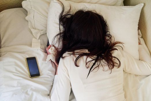 Nobody understand you better than your bed. High angle shot of a young woman lying in bed with tissues and her cellphone next to her.