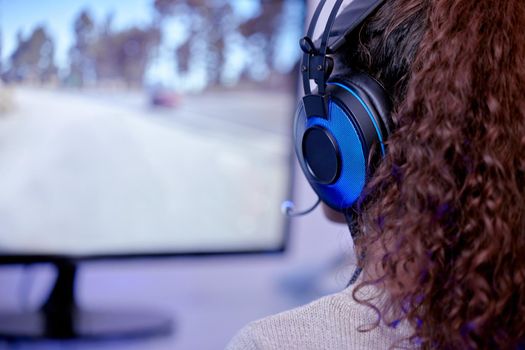 Shes one tough player. Rearview shot of a woman wearing a headset while playing video games.