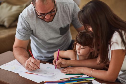 Shot of a mother and father drawing together with their young daughter at home.