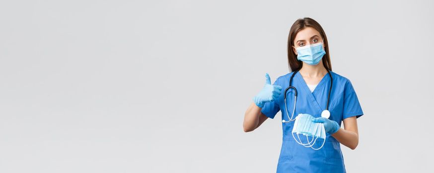 Covid-19, preventing virus, health, healthcare workers and quarantine concept. Professional female nurse or doctor in blue scrubs and personal protective equipment, recommend use medical masks