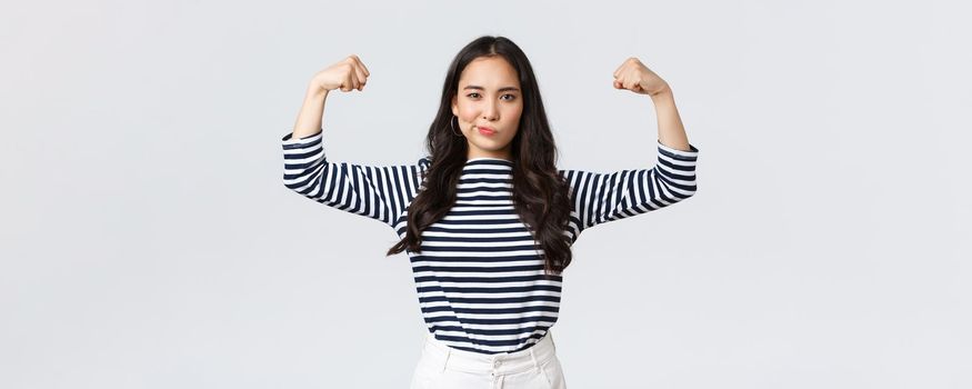 Lifestyle, people emotions and casual concept. Strong and confident asian woman flex biceps, bragging her perfect shape after sign-up gym membership, brag with muscles, workout and feeling strong