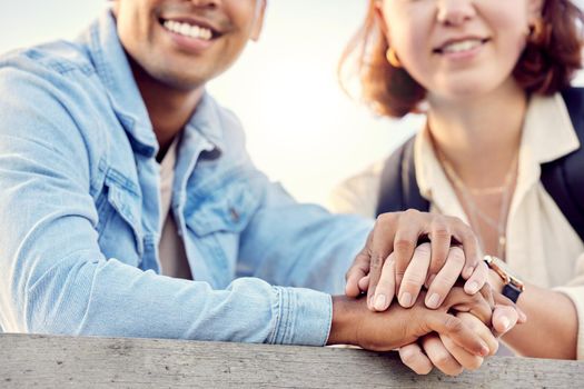 Cropped shot of a young couple holding hands while standing outside.