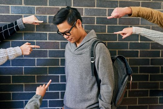 Bullying is a serious issue. Cropped shot of a young male university student being bullied while standing in a campus corridor.