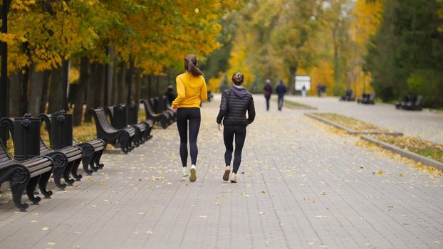 Young fit women running in autumn park.