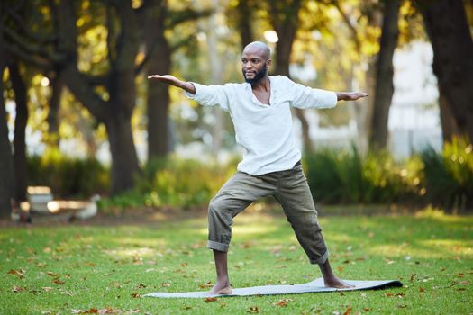 Full length shot of a handsome young man practicing yoga outside in the park.