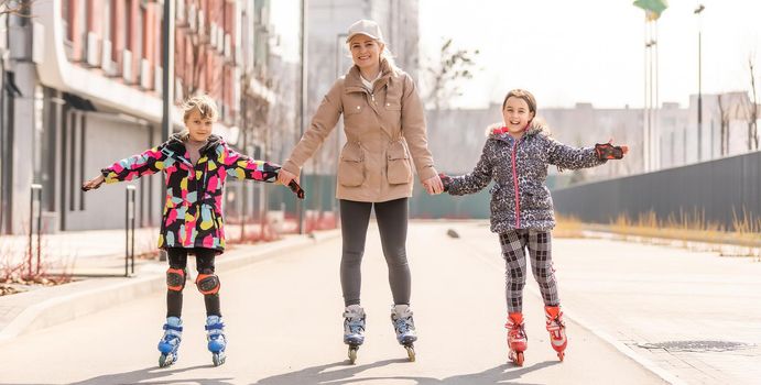 mother teaches daughter to roller skate.