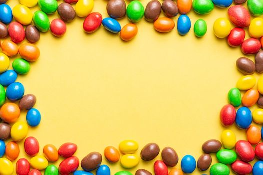 colored crunchy chocolate balls placed on yellow background