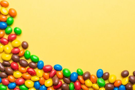 colored crunchy chocolate balls placed on yellow background