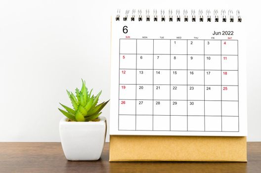 June 2022 desk calendar with plant pot on wooden table.