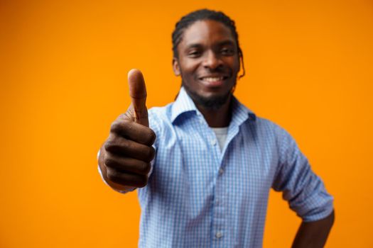 Smiling black man giving ok sign isolated on yellow background