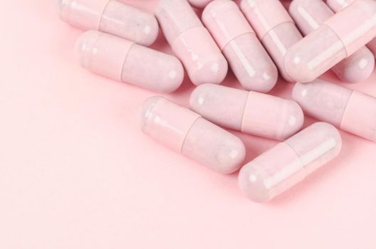 Pink capsule pills on pink background 