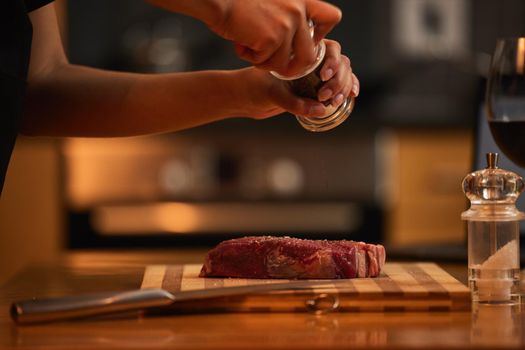 Meat should always be well seasoned. Shot of a woman seasoning a piece of steak for dinner.