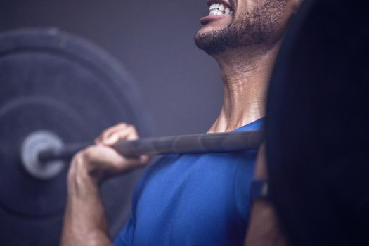 Hard work, hard muscles. Shot of an unrecognisable man working out with a barbell at the gym.