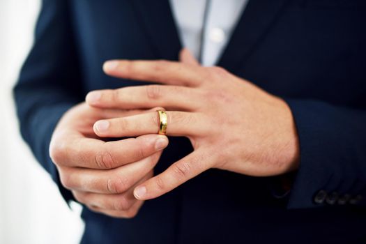 Wedding rings are symbols of commitment, promise and loyalty. Cropped shot of an unrecognizable bridegroom adjusting his ring on his wedding day.
