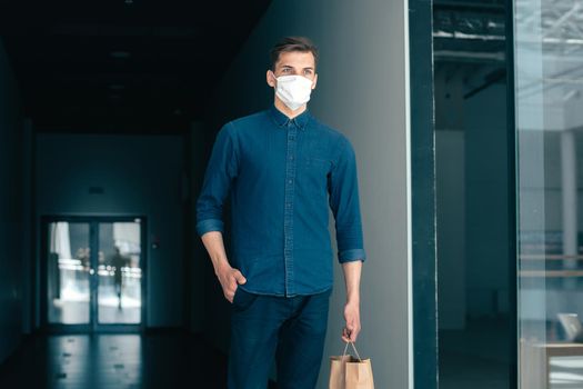young man in a protective mask walking along a city street