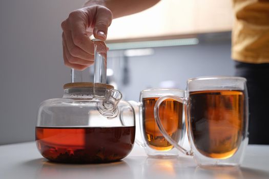 Black tea in a transparent teapot and cups closeup