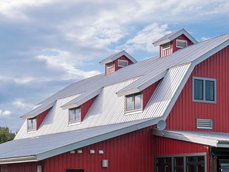 Top roof of new red barn on cloudy sky background