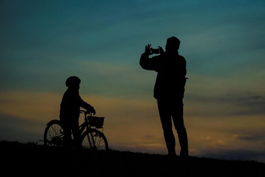 Silhouette of parent and child standing on sunset hill