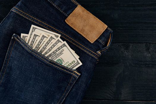 Pocket money. Dollar in hip pocket of worn blue jeans. Close-up.