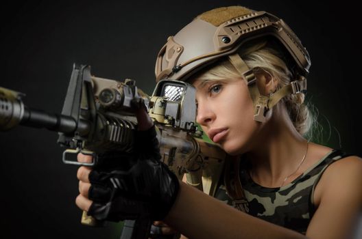 a girl soldier armed with an automatic rifle takes aim