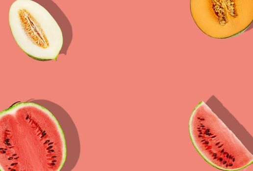 Delicious melons of different varieties and watermelon, halves and slices, on pink background with copy space for text or images. Close-up, top view.
