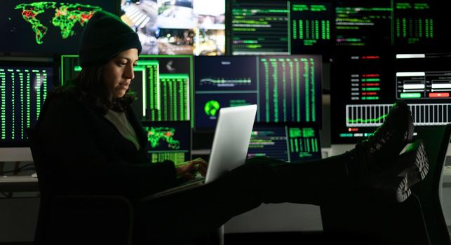 Horizontal banner image of hispanic female hacker hacking security firewall late at night. Multiple screen background.