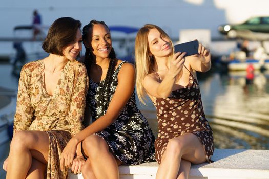 Content diverse girlfriends taking selfie on pier