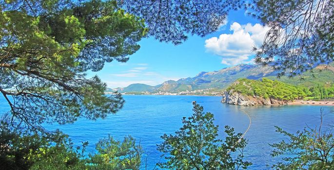 Stunning landscape view on the blue Adtiatic Sea and mountains framed by the pine trees near the Sveti Stefan, Montenegro