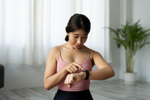 Asian woman setting up the fitness smart watch for workout fitness at home.