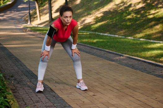 Female runner, Latin American sportswoman feeling exhaustion while jogging on the running track or treadmill in the city park. Active lifestyle, body weight training, slimming and dieting concept